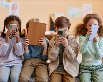 kids covering their faces with phones and tablets