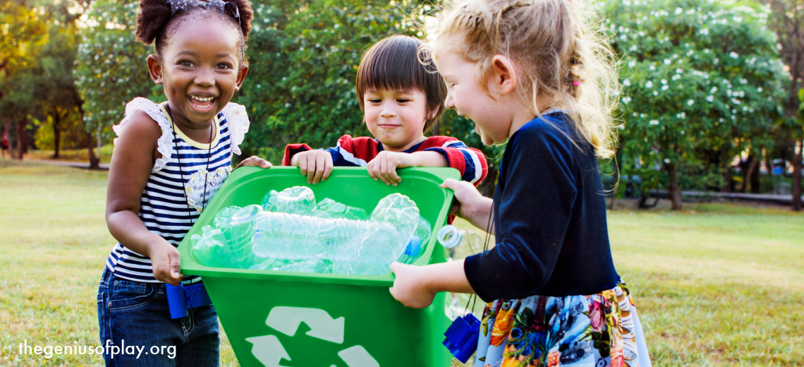 three elementary school age kids carrying a recycling bucket